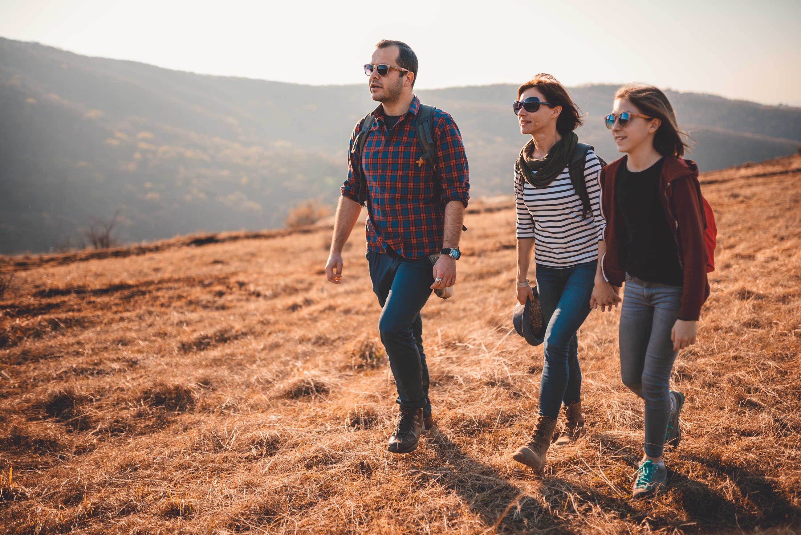 A family with a teenager hiking together on a sunny day