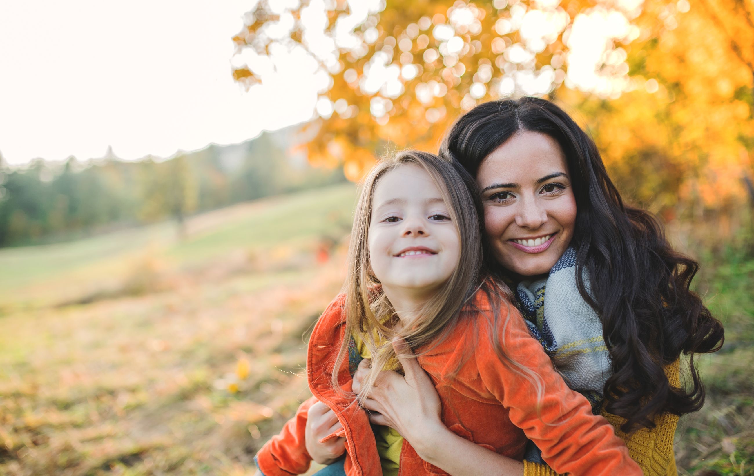 A mother and daughter laughing outdoors in autumn