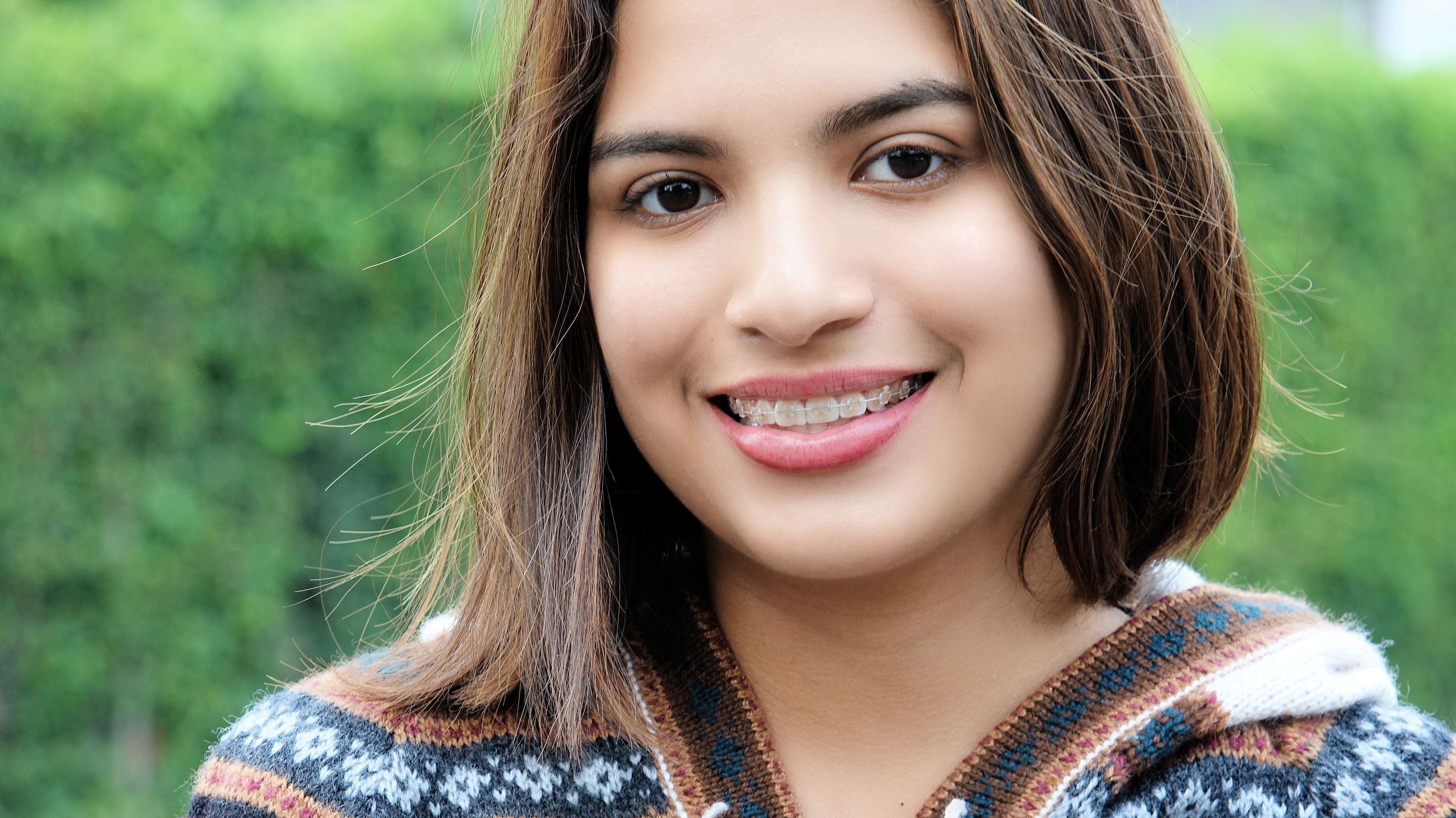 A smiling teenage girl with braces outdoors