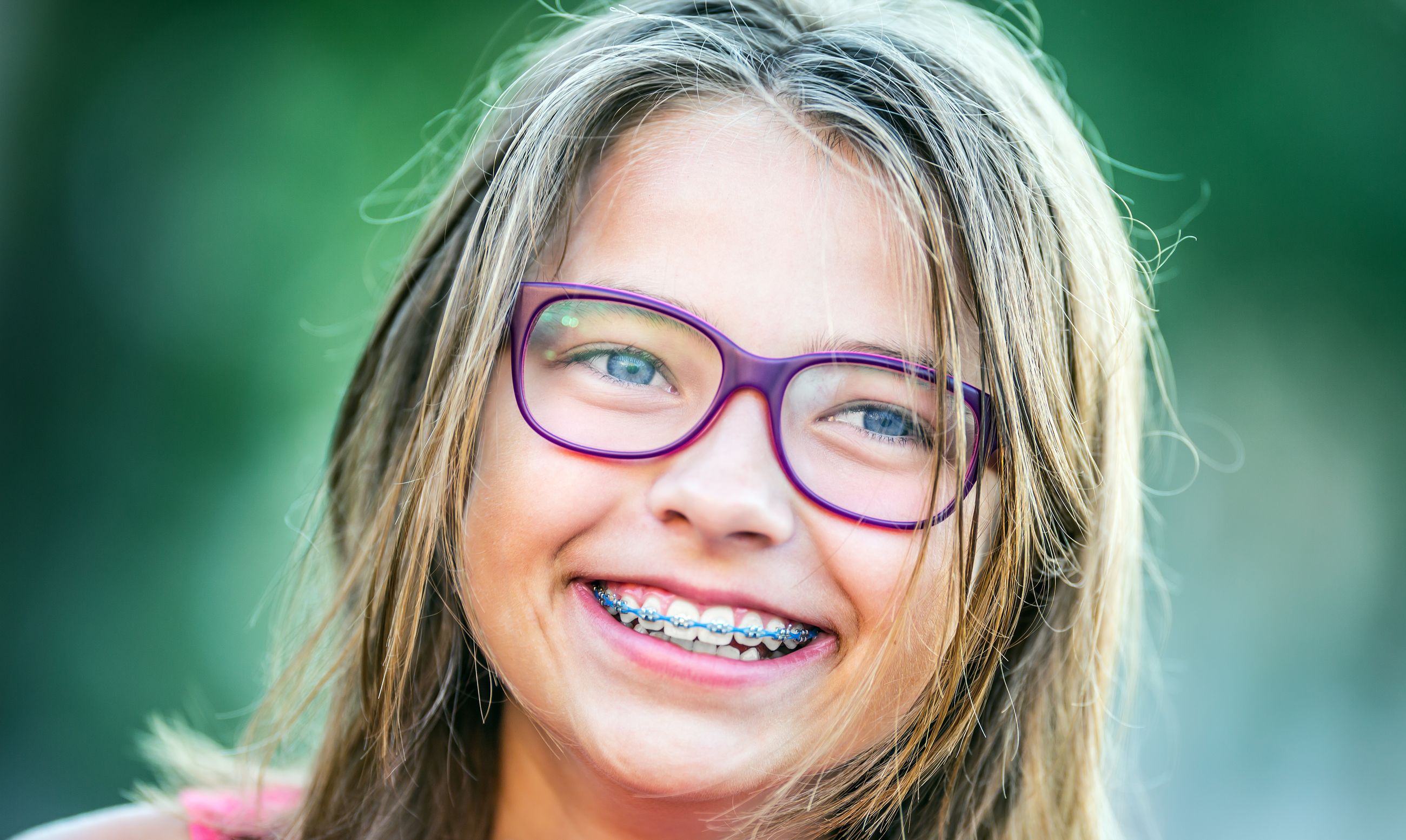 A teenage girl in glasses laughing with braces